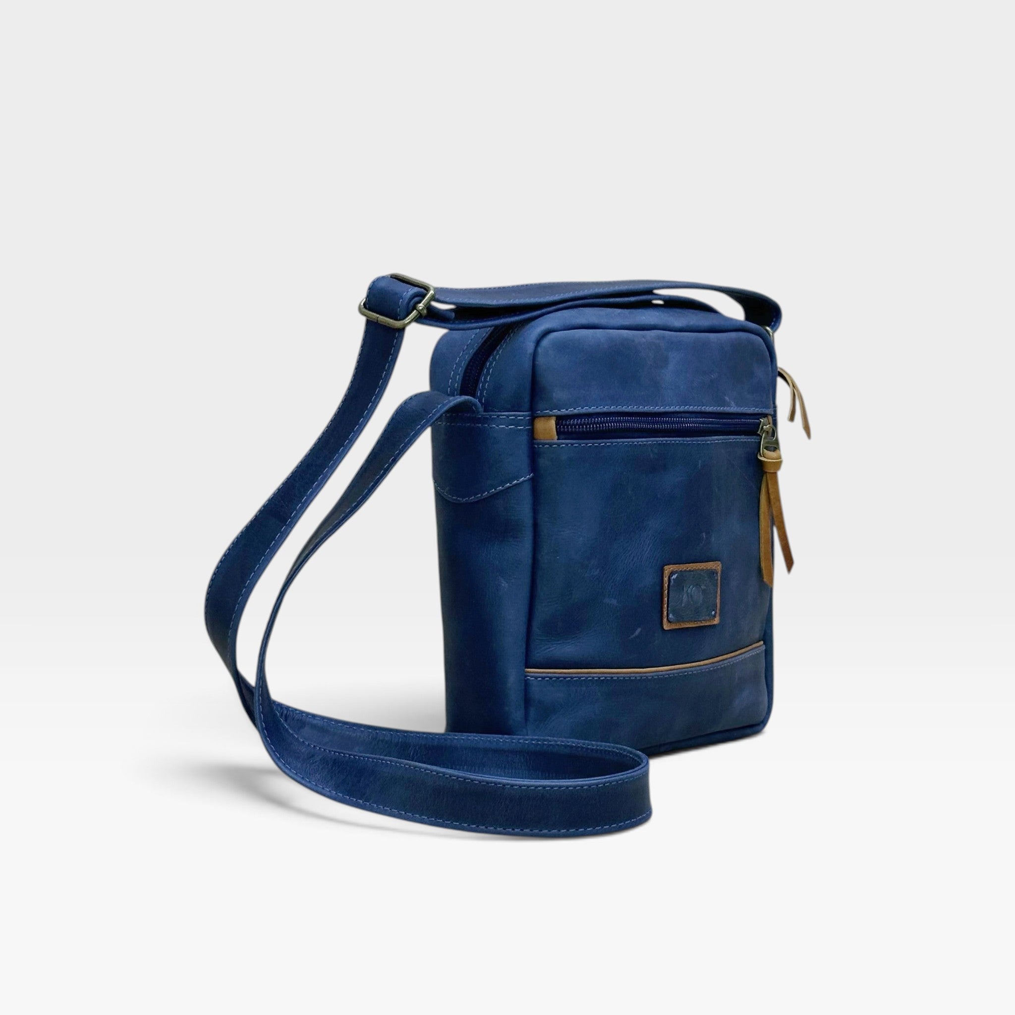 Bolso manos libres kopelletteria en cuero rústico azul con acentos miel, diseño cruzado minimalista y correa ajustable.