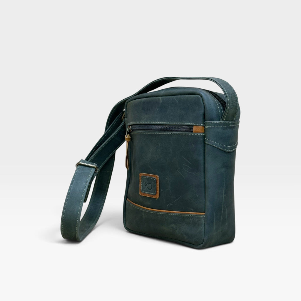 Bolso manos libres kopelletteria en cuero rústico azul profundo con detalles en color miel y correa ajustable.
