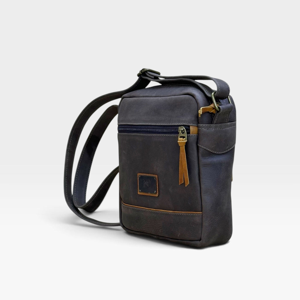 Bolso manos libres kopelletteria en cuero rústico azul profundo con detalles en color miel y correa ajustable.