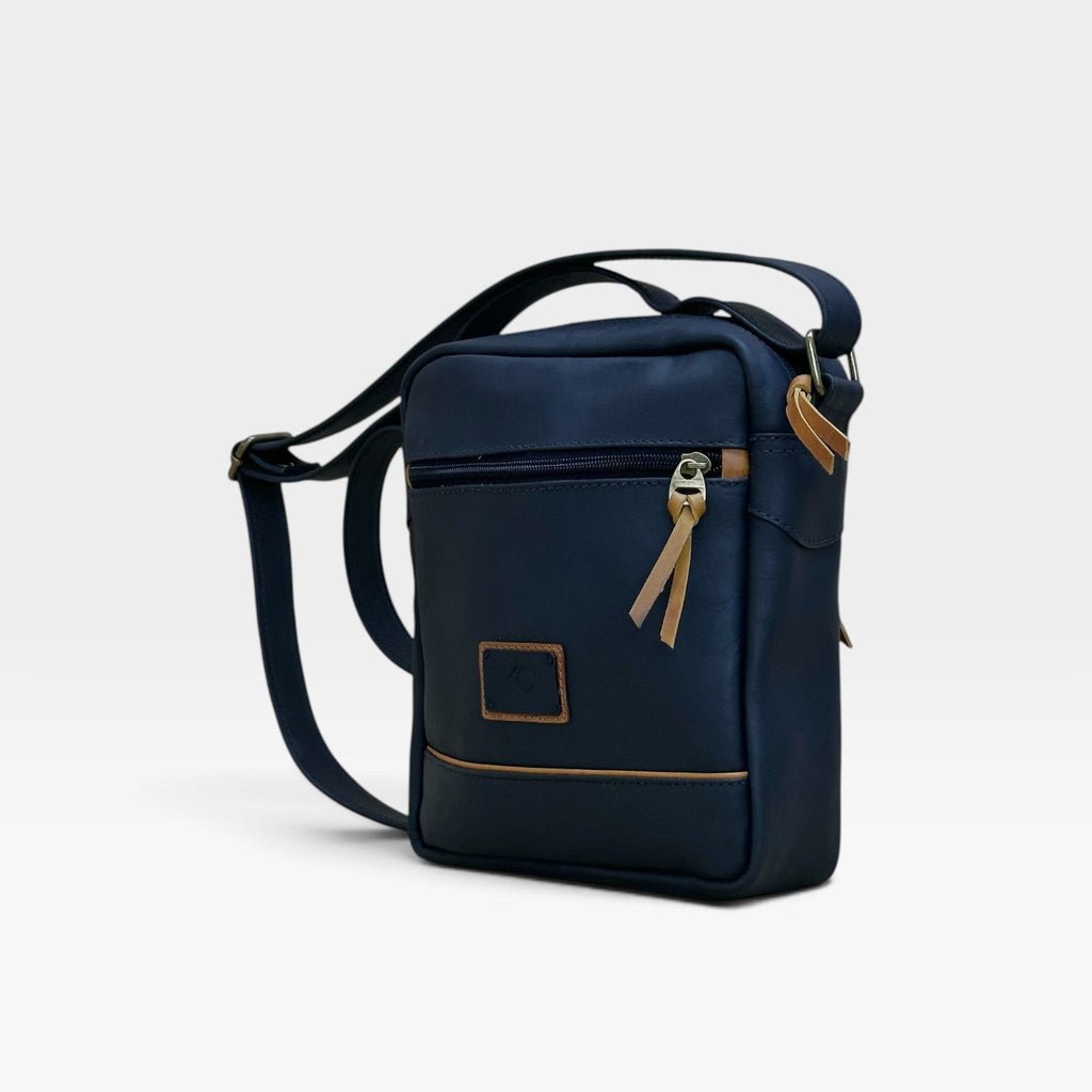 Bolso manos libres kopelletteria azul profundo en cuero genuino rústico con detalles en color miel y correa ajustable.