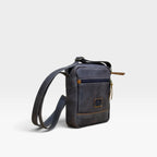 Bolso manos libres kopelletteria en cuero rústico azul profundo con detalles en color miel y correa ajustable.