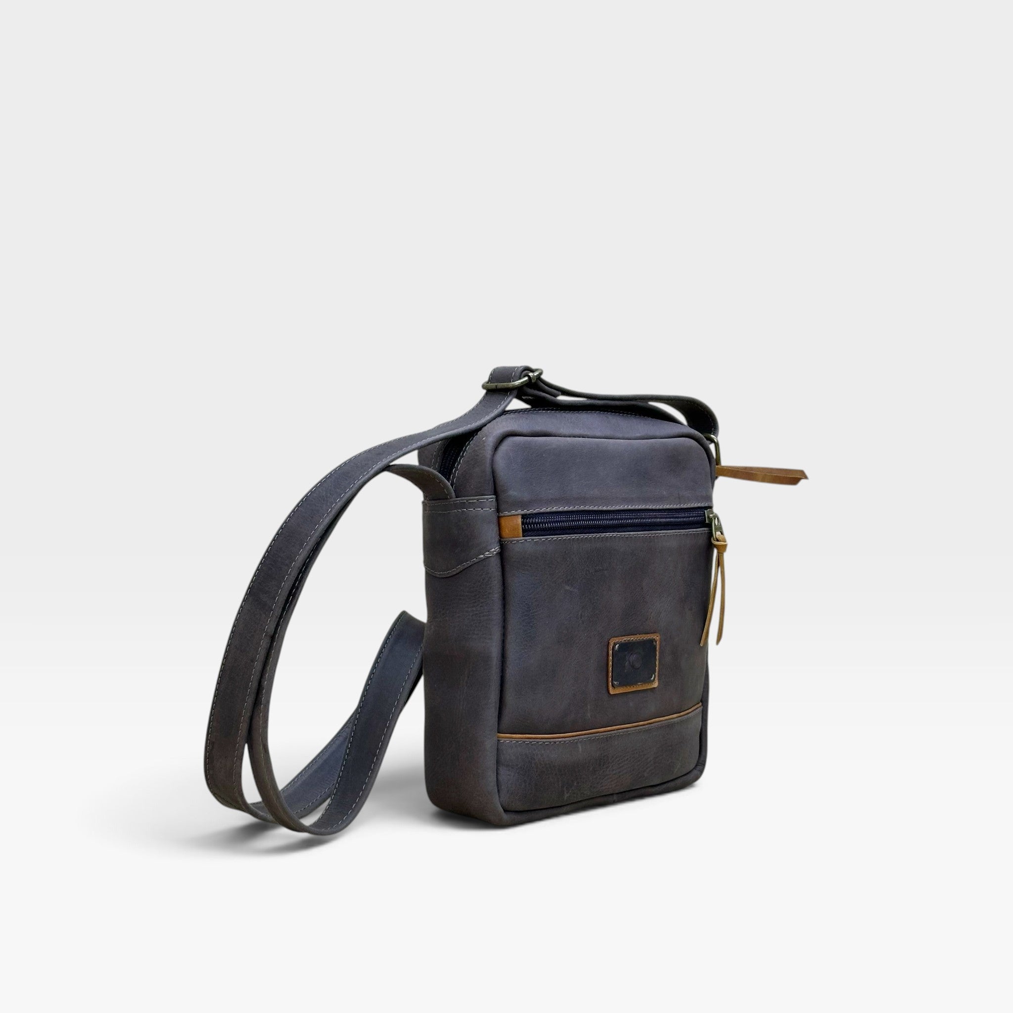 Bolso manos libres kopelletteria en cuero rústico azul profundo con detalles en color miel y correa ajustable.