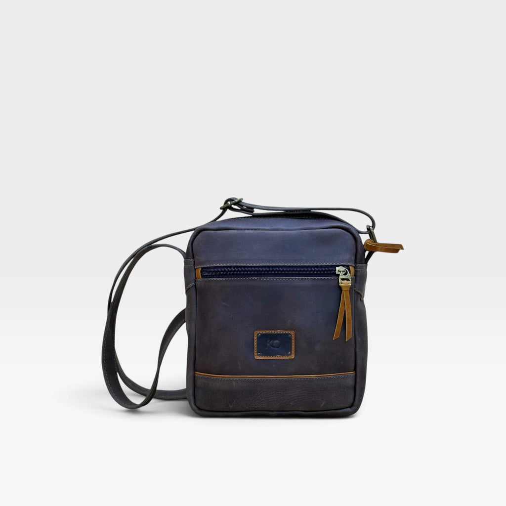 Bolso manos libres kopelletteria en cuero azul profundo con acentos miel, diseño minimalista y tres compartimentos.