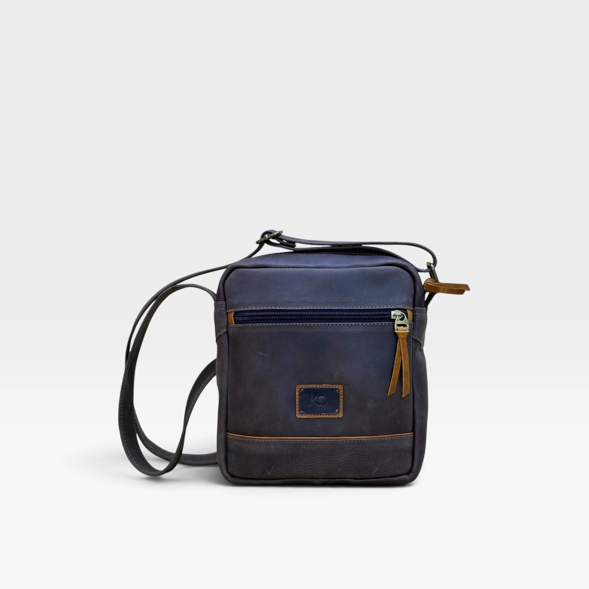 Bolso manos libres kopelletteria en cuero azul profundo con acentos miel, diseño minimalista y tres compartimentos.