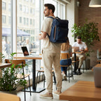 Hombre con morral azul de cuero kopelletteria en una cafetería, ideal para laptop y uso urbano profesional.