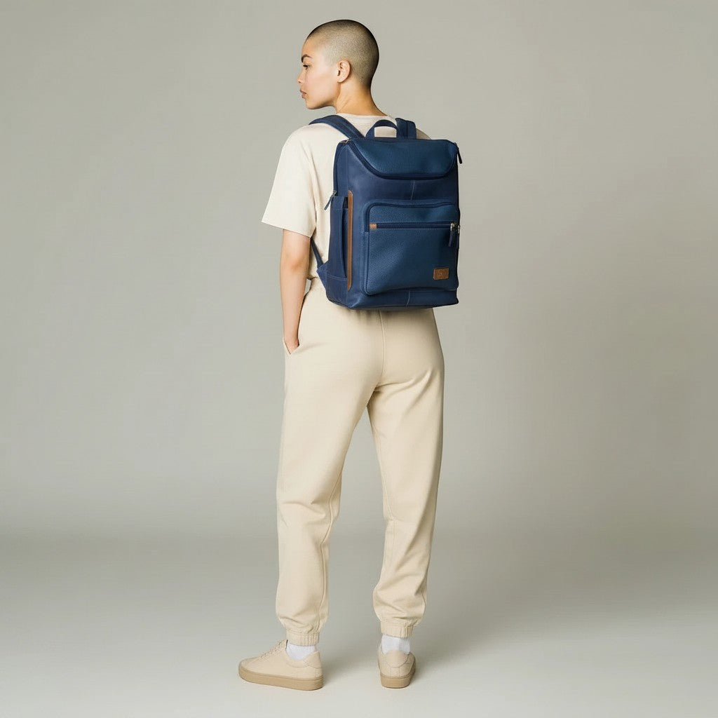 Persona con morral kopelletteria azul de cuero genuino, diseño minimalista con compartimento para laptop y detalles.